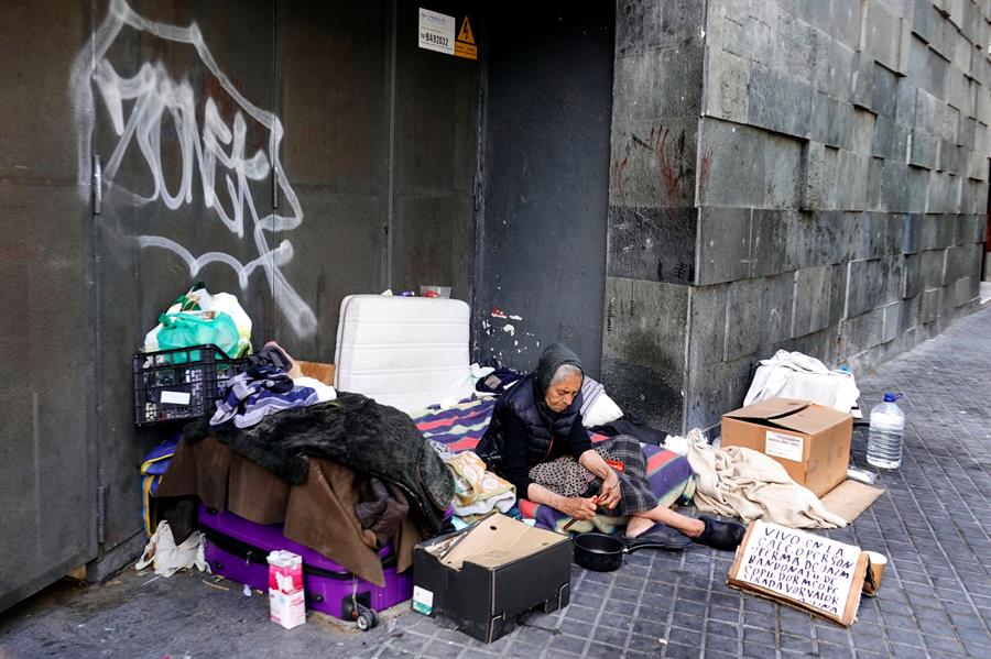 Una mujer sin hogar prepara su cena en las calles de Barcelona. (EFE)