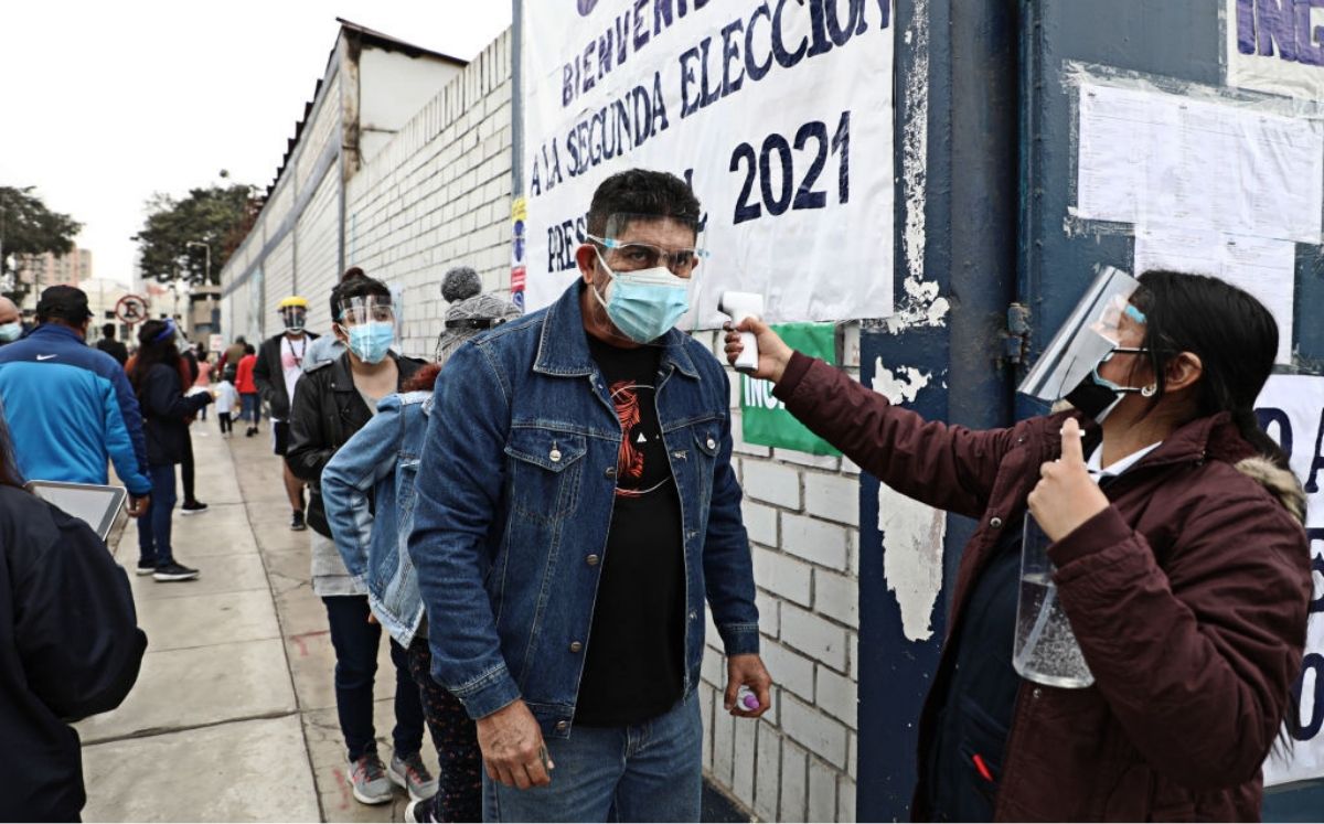 Funcionaria toma la temperatura de un ciudadano antes de ingresar a una mesa electoral en Lima, Perú. 6 de junio 2021. (Klebher Vasquez/Anadolu Agency vía Getty Images)